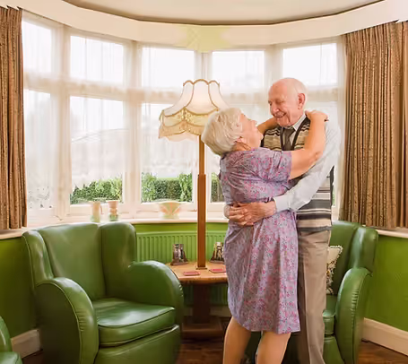 Two seniors dancing in a living room